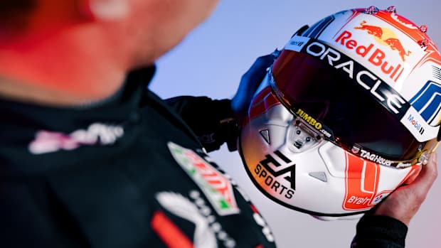 Max Verstappen holding an EA Sports-branded helmet.